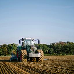 Ein Trecker auf einem Landwirtschaftlich genutzten Feld durchpflügt einen Acker.