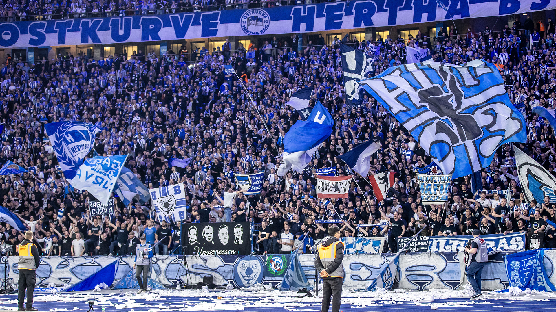 Fans von Hertha BSC feuern ihr Team aus der Ostkurve mit Flaggen an.