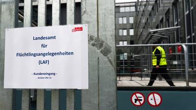 Ein Schild mit der Aufschrift "Landesamt für Flüchtlingsnagelegenheiten" hängt an einem Tor.