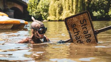 Ein Lahntaucher mit einem Straßenschild in einem Fluss.