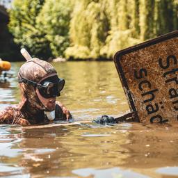 Ein Lahntaucher mit einem Straßenschild in einem Fluss.