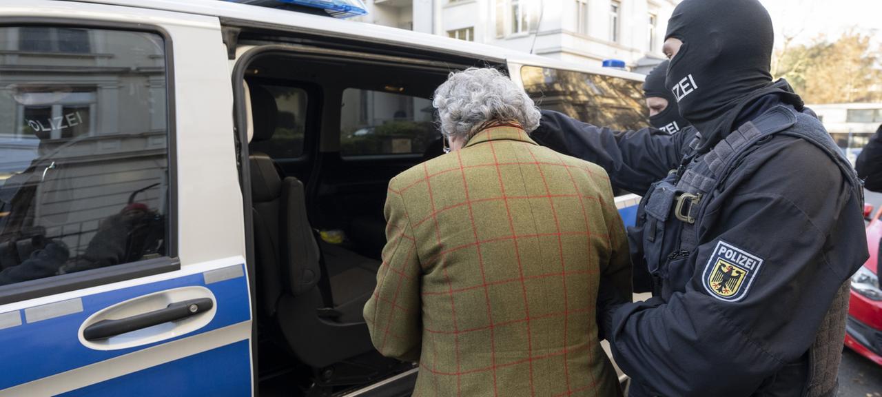 Bei einer Razzia gegen "Reichsbürger" führen vermummte Polizisten nach der Durchsuchung eines Hauses Heinrich XIII Prinz Reuß zu einem Polizeifahrzeug.