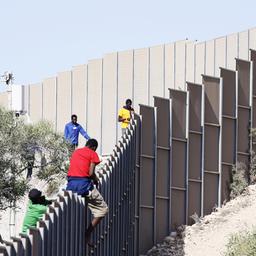 Migranten klettern über einen Zaun auf der Insel Lampedusa.