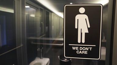 Geschlechtsneutrales Piktogramm am Eingang einer Hoteltoilette mit der Aufschrift: "We don't care" (deutsch: "Uns egal").
