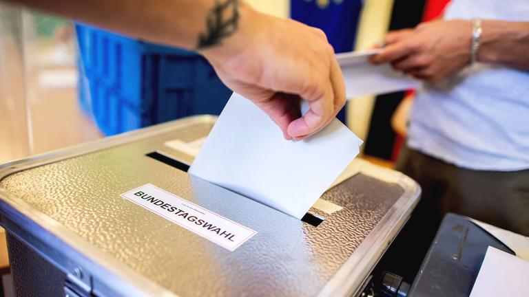 Ein Wähler wirft in einem Wahllokal seinen Stimmzettel für die Bundestagswahl in eine Wahlurne. 