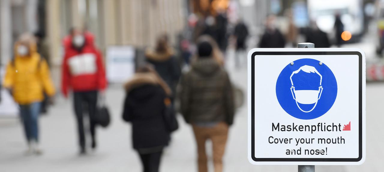 Ein Schild weist in der Münchner Innenstadt auf die Maskenpflicht innerhalb der Fußgängerzone hin.