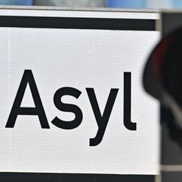 Eine rote Ampel leuchtet vor dem Wort "Asyl" auf einem Wegweiser zur Erstaufnahme-Einrichtungen des Landes Brandenburg in Eisenhüttenstadt.
