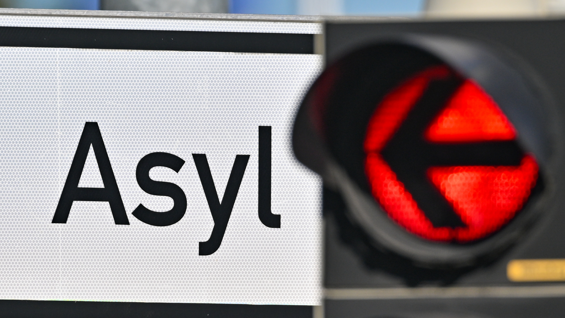 Eine rote Ampel leuchtet vor dem Wort "Asyl" auf einem Wegweiser zur Erstaufnahme-Einrichtungen des Landes Brandenburg in Eisenhüttenstadt.