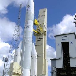 Die neue Ariane 6 Rakete steht startbereit an einem Turm.