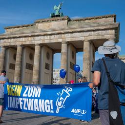 Teilnehmer halten ein Plakat mit der Aufschrift «Nein zum Impfzwang» des österreichischen Senders AUF1 bei einer Kundgebung vor dem Brandenburger Tor in Berlin.