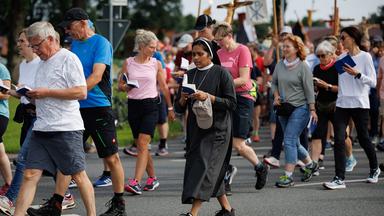Ordensschwestern und Pilger der Telgter Wallfahrt gehen in Glandorf mit Gesangsbuch auf einer Straße. 