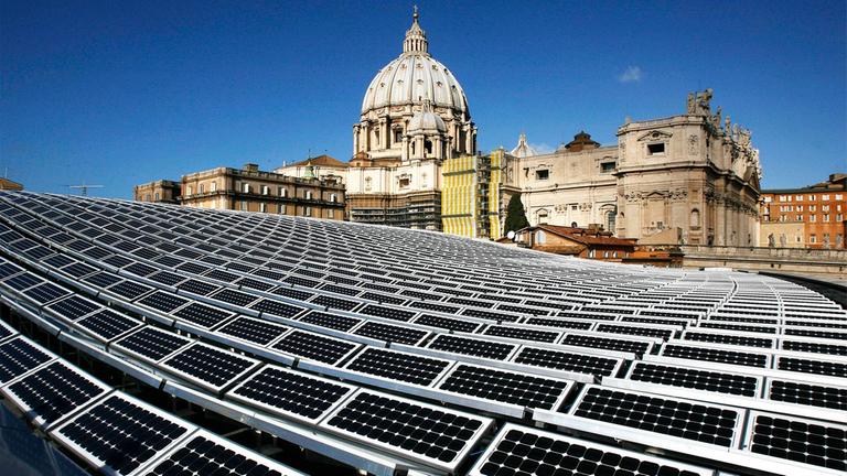 Solaranlage auf dem Dach des Vatikans, mit dem Petersdom im Hintergrund.