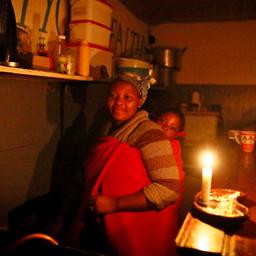 Bei Kerzenlicht: Eine Frau mit Kind, während in Kapstadt der Strom abgestellt ist.