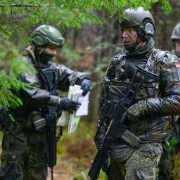 Soldaten der Bundeswehr stehen bei Regen während einer Übung im Wald.