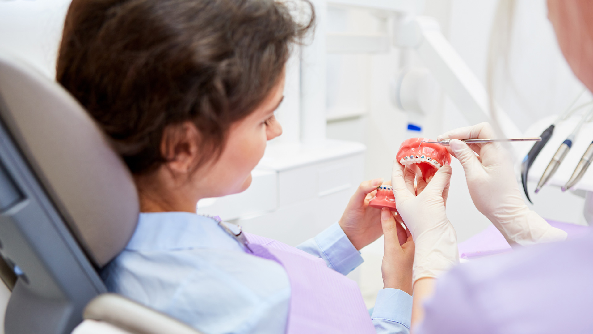 Eine Patientin und eine medizinische Fachkraft schauen gemeinsam auf ein Gebiss mit Zahnspange.