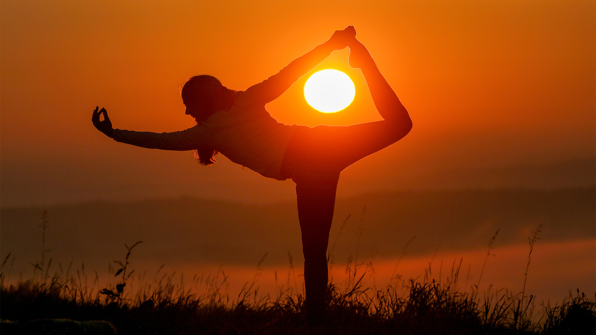 Eine Frau praktiziert Yoga in der Morgensonne