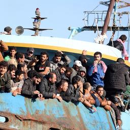 Migranten stehen an Bord eines Fischerbootes.