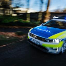 Ein mit Bewegungsunschärfe abgelichtetes Polizeiauto fährt mit Blaulicht eine Straße entlang.