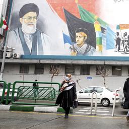 Menschen gehen in der Innenstadt von Teheran unter einem riesigen Wandgemälde von Ayatollah Ruhollah Khomeini (r.) und Ayatollah Ali Khamenei (l.) entlang.