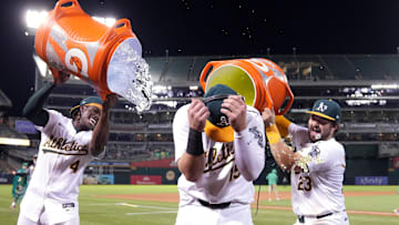 Sep 6, 2024; Oakland, California, USA; Oakland Athletics left fielder Seth Brown (center) reacts as right fielder Lawrence Butler (4) and catcher Shea Langeliers (23) dumps water and Gatorade after defeating the Detroit Tigers at Oakland-Alameda County Coliseum. Mandatory Credit: Darren Yamashita-Imagn Images