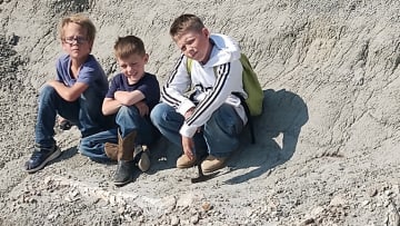 Kaiden Madsen, Liam Fisher, and Jessin Fisher pose in front of their latest find. Their father, Sam Fisher, texted this photo to his high school classmate Tyler Lyson, setting the stage for a remarkable discovery.