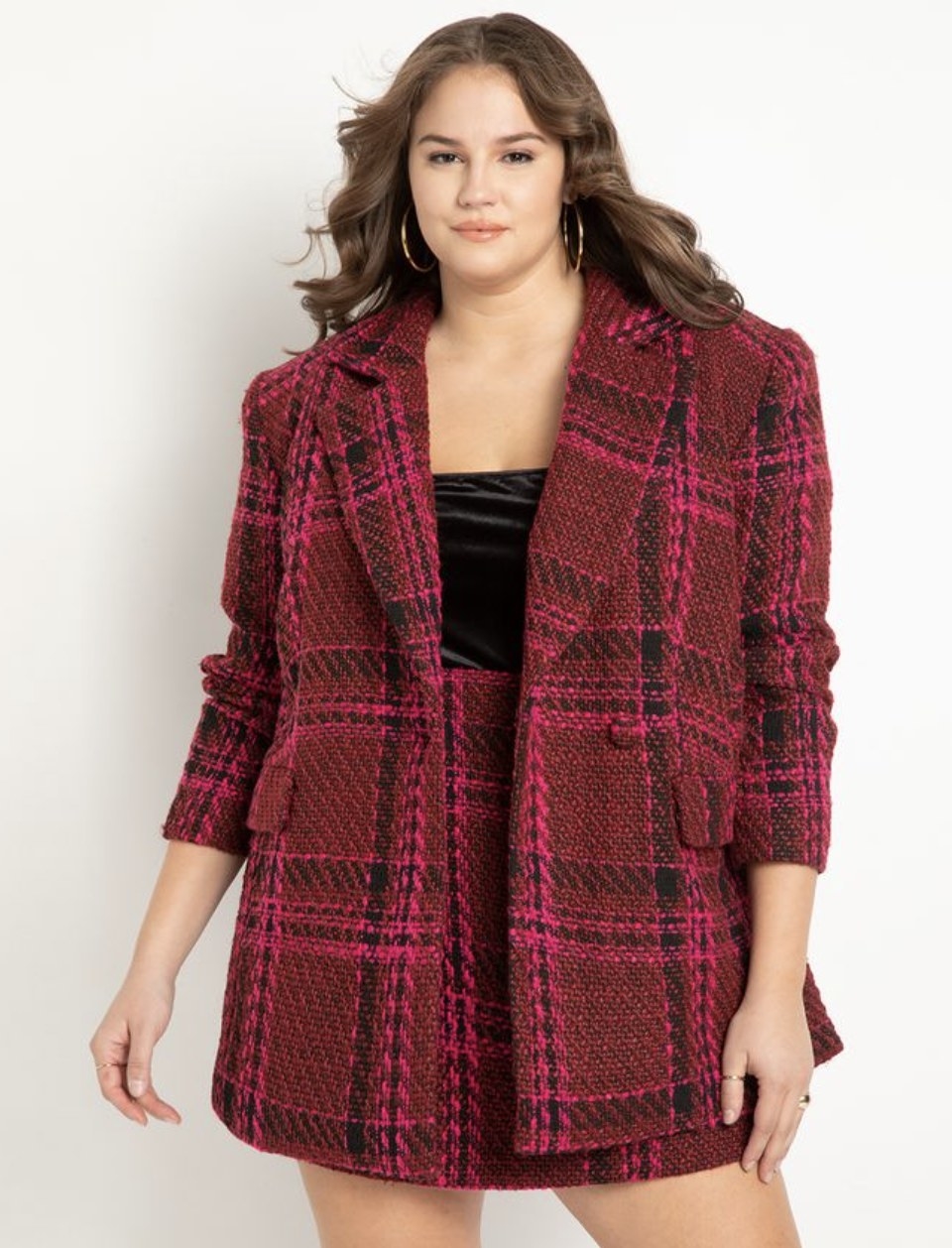 The model wears the red and pink tweed blazer and matching skirt