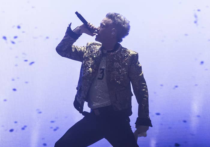 Cantante en concierto con chaqueta brillante, actitud dinámica, micrófono en mano