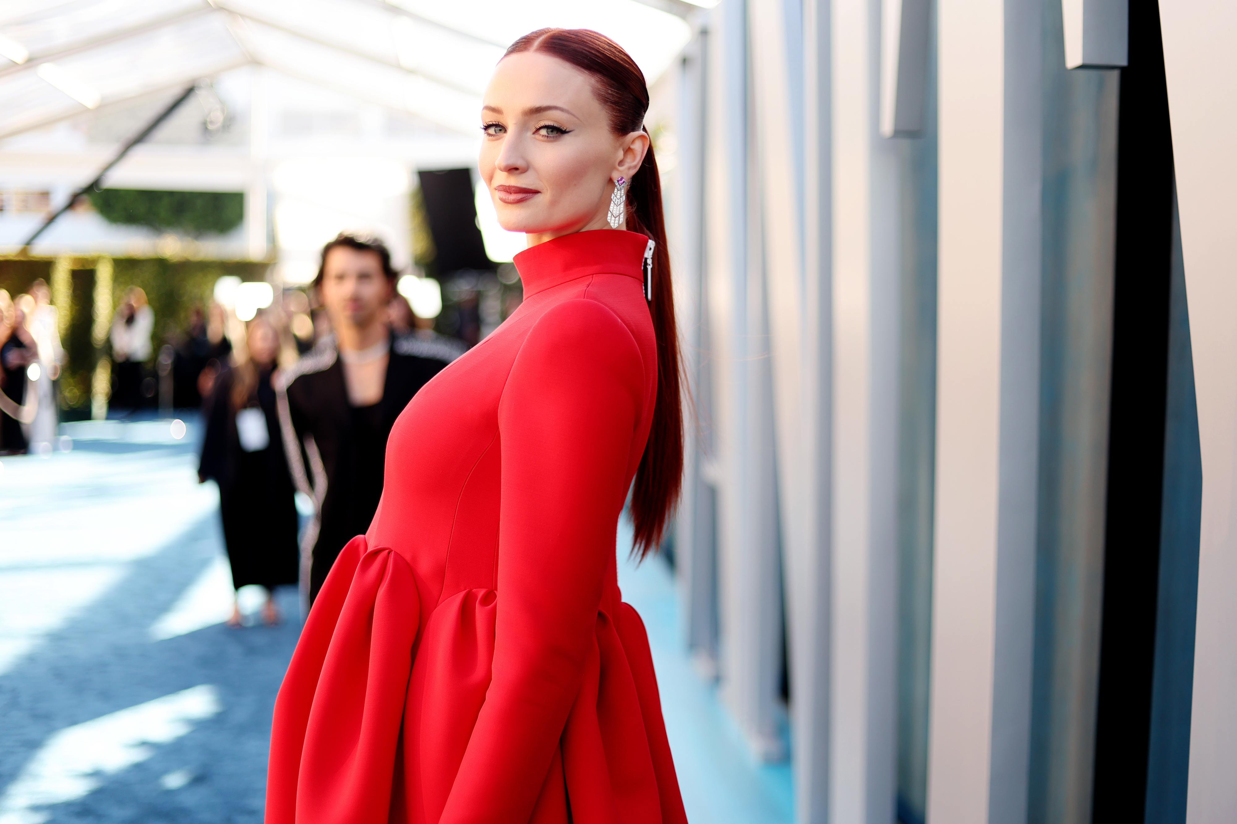 Sophie Turner in a high-neck dress posing on the carpet