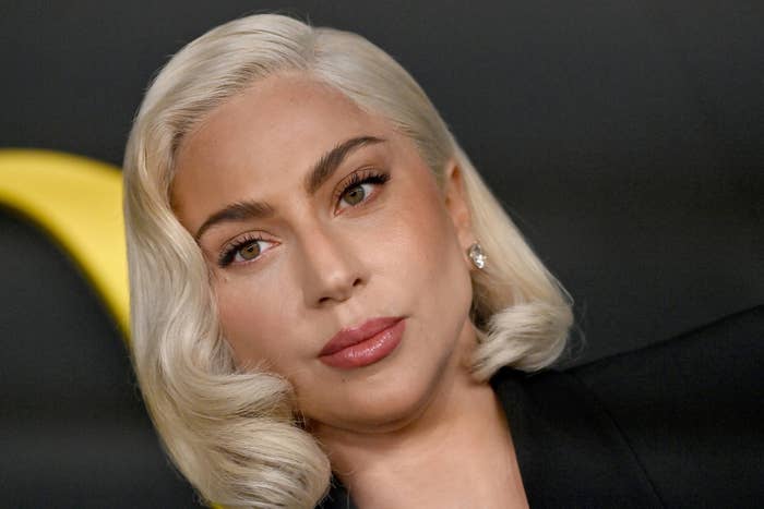 Lady Gaga with platinum blonde hair in loose waves, wearing simple makeup and diamond earrings, attends a formal event