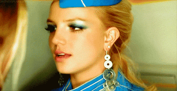 Britney Spears in a flight attendant costume, as seen in her iconic &quot;Toxic&quot; music video. Her outfit includes a blue hat, sparkling earrings, and dramatic eye makeup