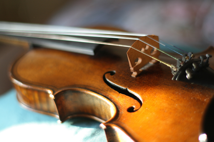 Close-up image of a violin showing its strings and bridge, highlighting the intricate craftsmanship and polished wood