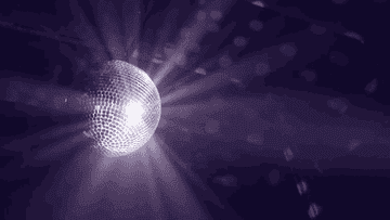 Una bola de discoteca giratoria refleja luces en un entorno oscuro, creando un ambiente festivo y musical