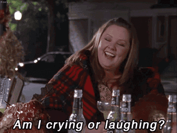 Melissa McCarthy at an outdoor table, smiling and laughing with the text &quot;Am I crying or laughing?&quot; in front of her