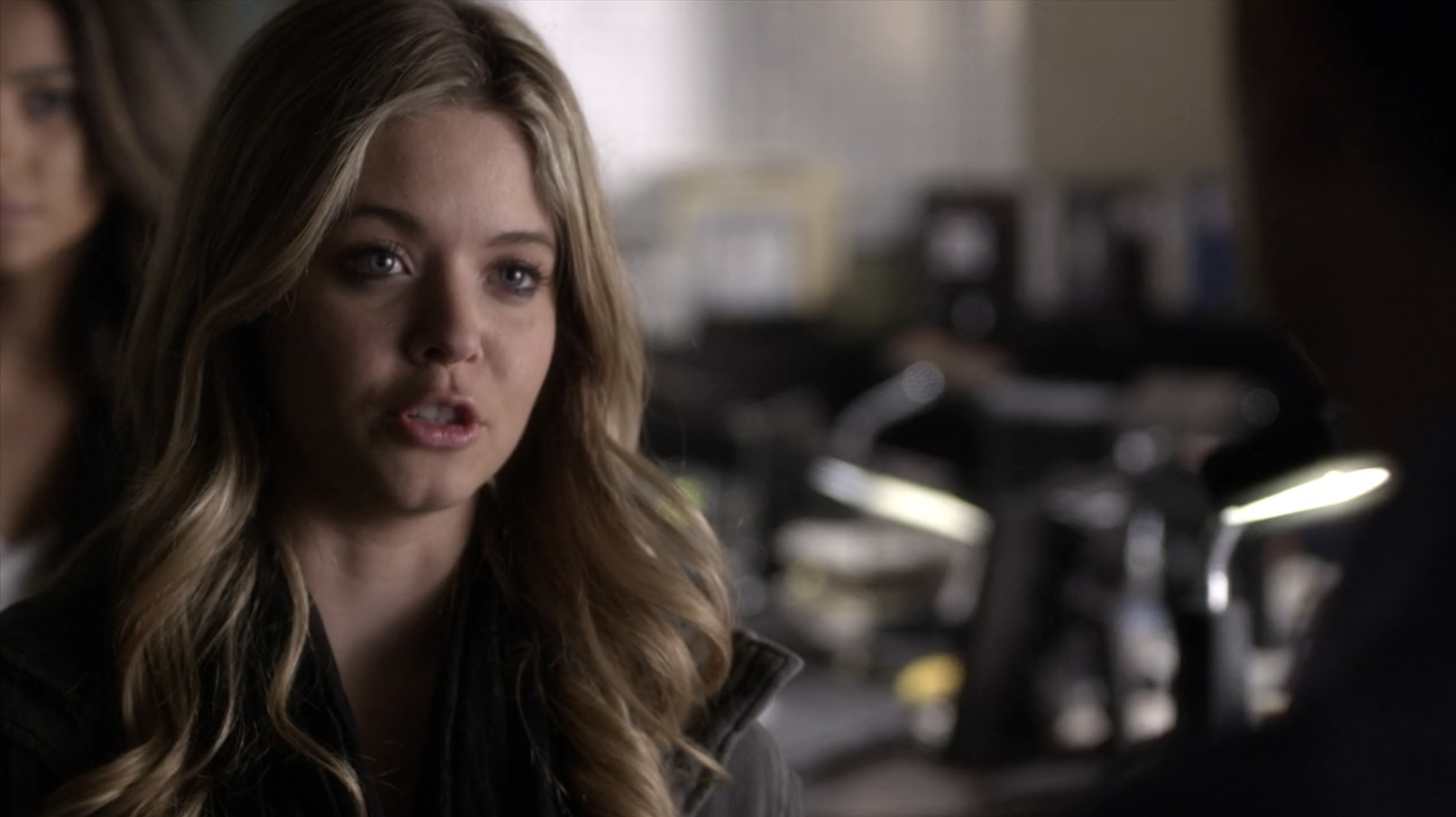 Sasha Pieterse, wearing a dark outfit, speaks seriously while indoors