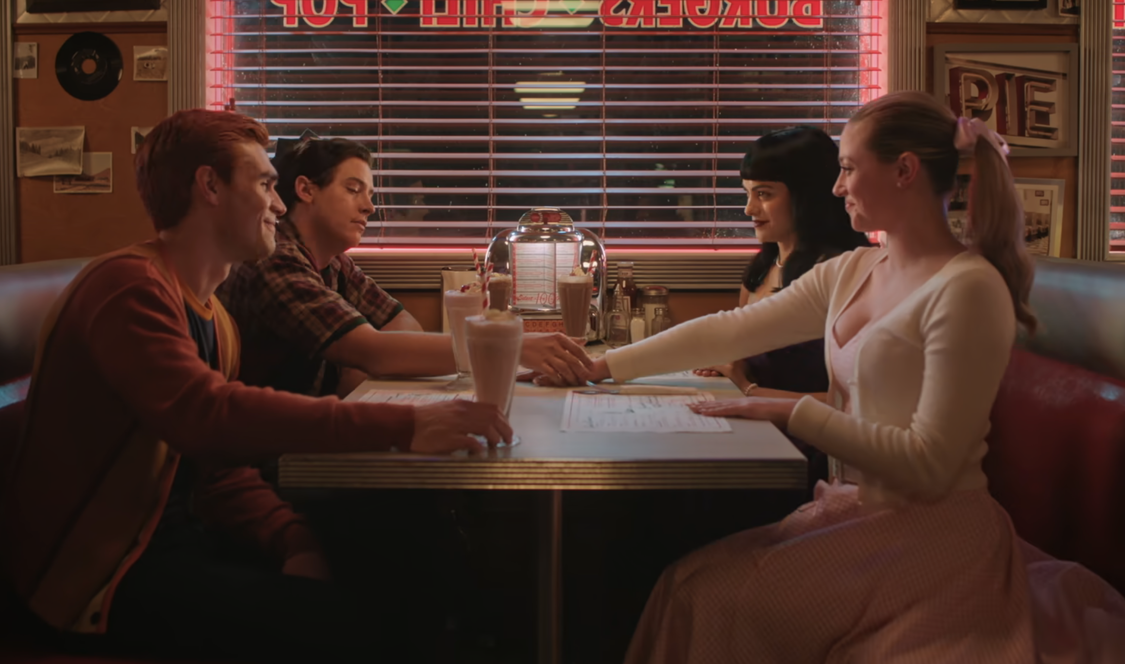 KJ Apa, Cole Sprouse, Camila Mendes, and Lili Reinhart sit in a classic diner booth, dressed in &#x27;50s clothing