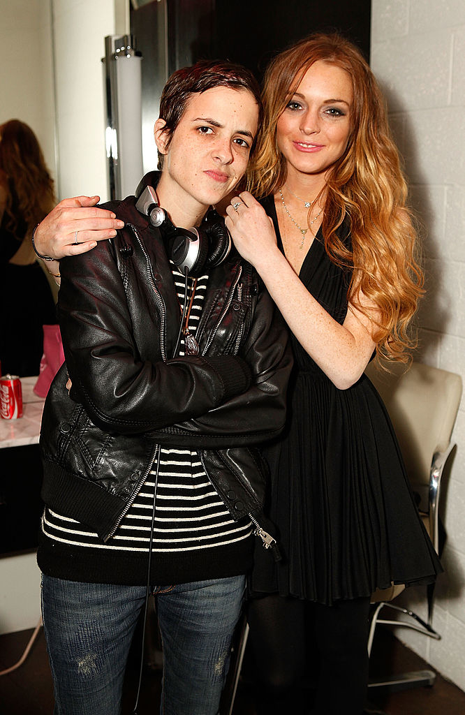 Samantha Ronson in a leather jacket with headphones around her neck, and Lindsay Lohan in a dress pose together, smiling gently with Lohan&#x27;s hand on Ronson&#x27;s shoulder