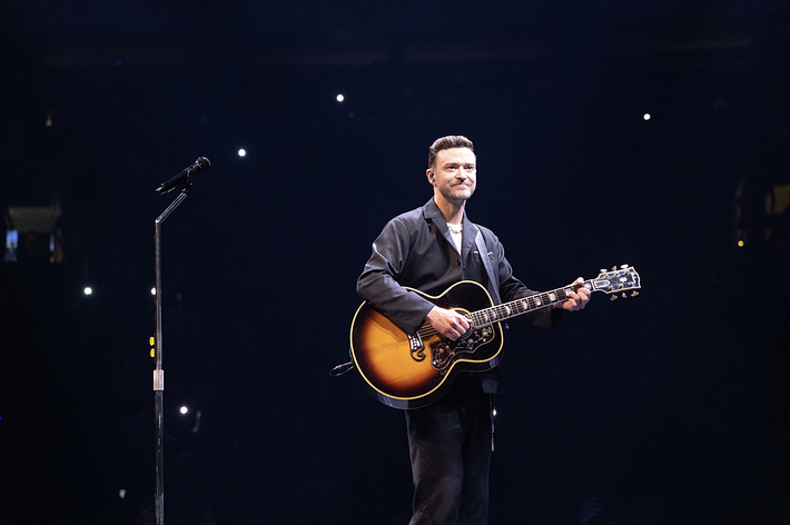 Man playing an acoustic guitar on stage during a performance