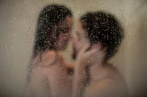 Two people sharing an intimate moment behind a foggy glass shower door. Their faces are close and their features are blurred by the condensation on the glass