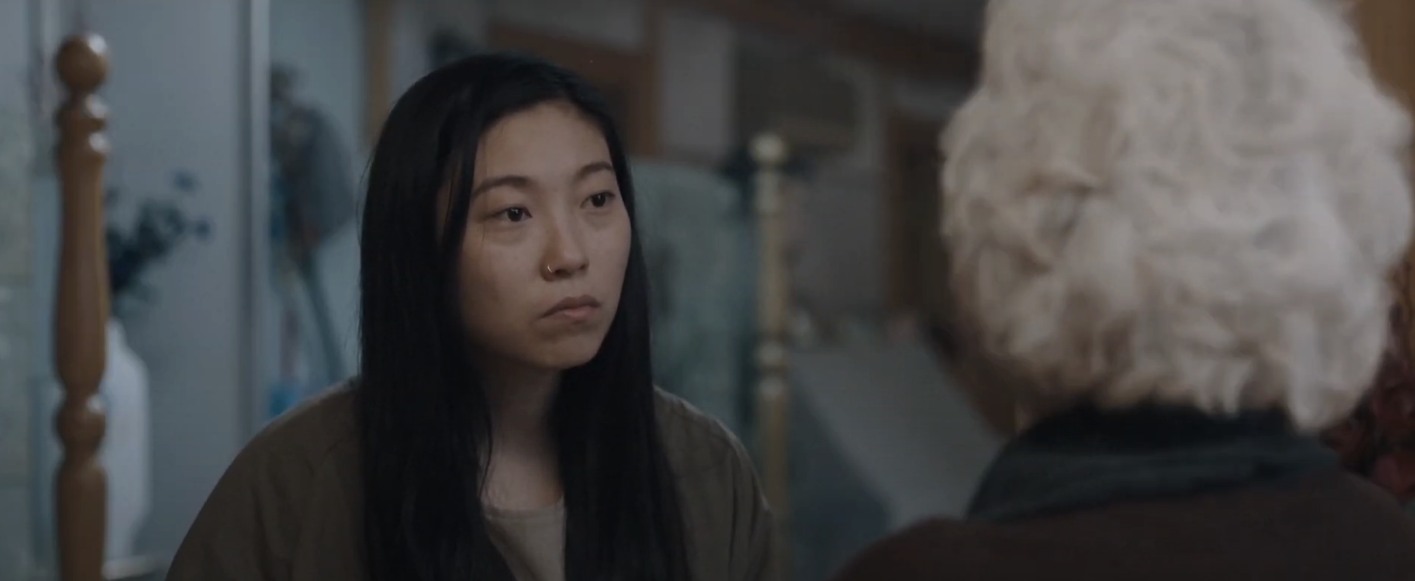 Awkwafina in a scene from a movie, looking at a person with white hair whose back is to the camera