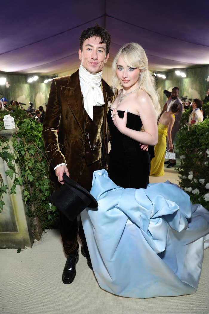 Barry Keoghan in a velvet suit and white ascot, and Sabrina Carpenter in a strapless gown with blue train at a formal event