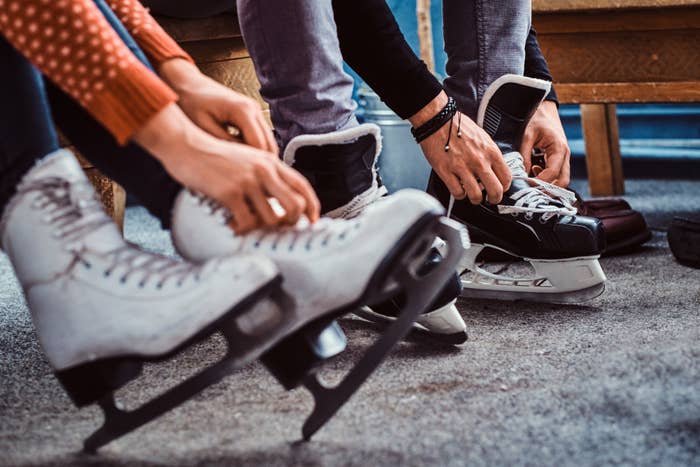 People lacing up figure skates and hockey skates, preparing to go ice skating