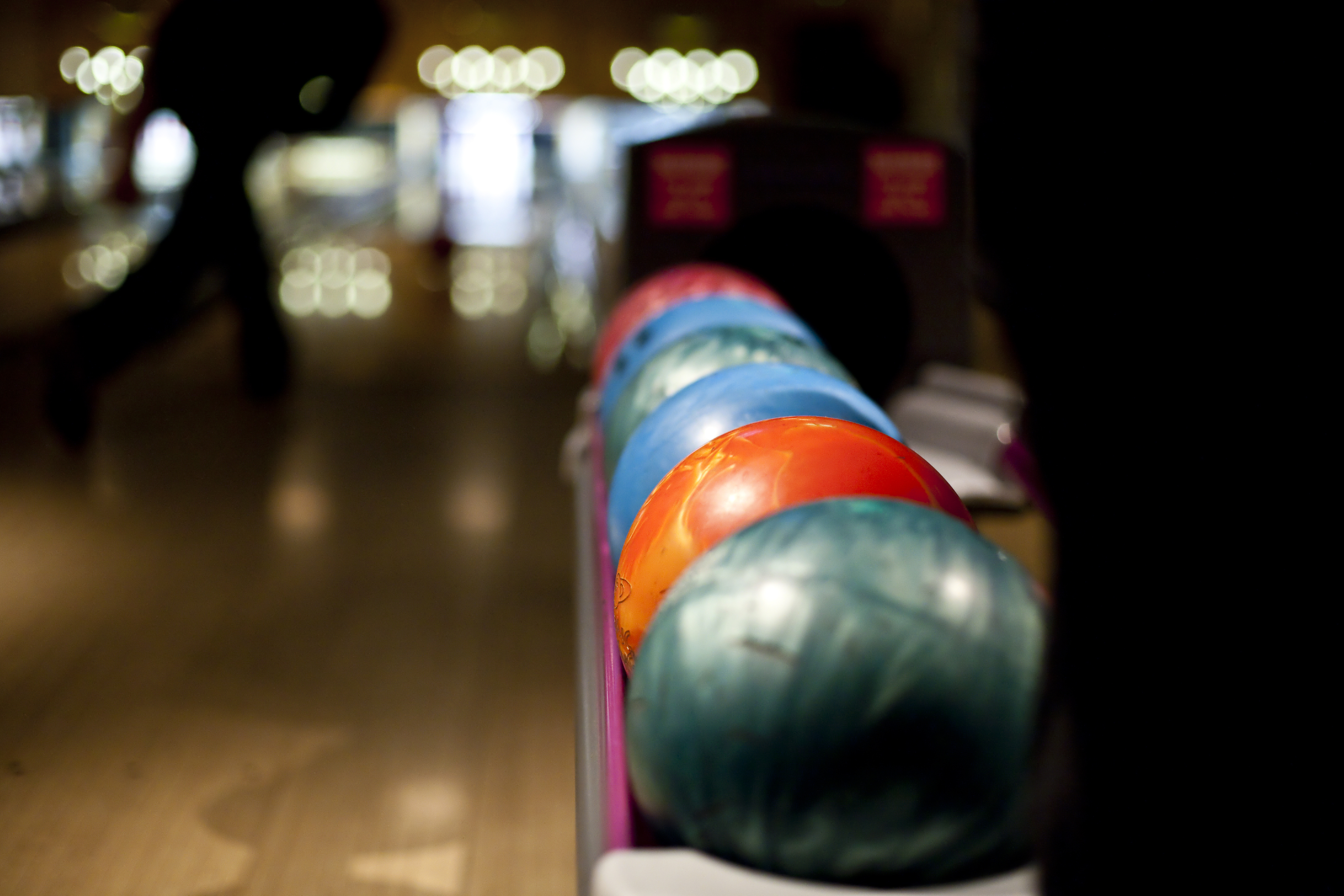A row of bowling balls at a bowling alley.