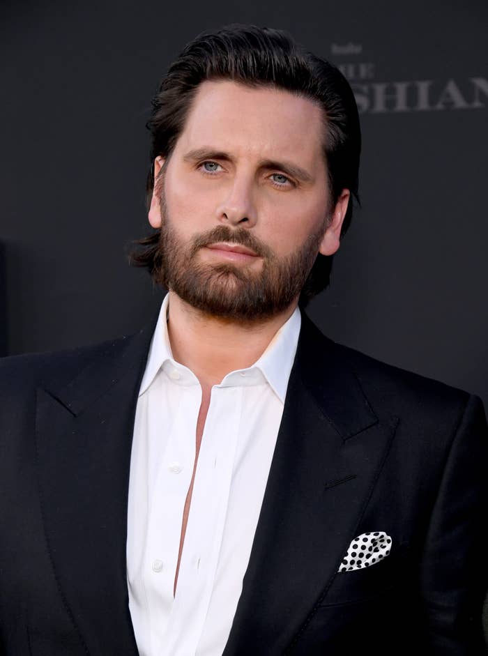 Scott Disick in a dark suit and shirt with a polka-dot pocket square at a formal event