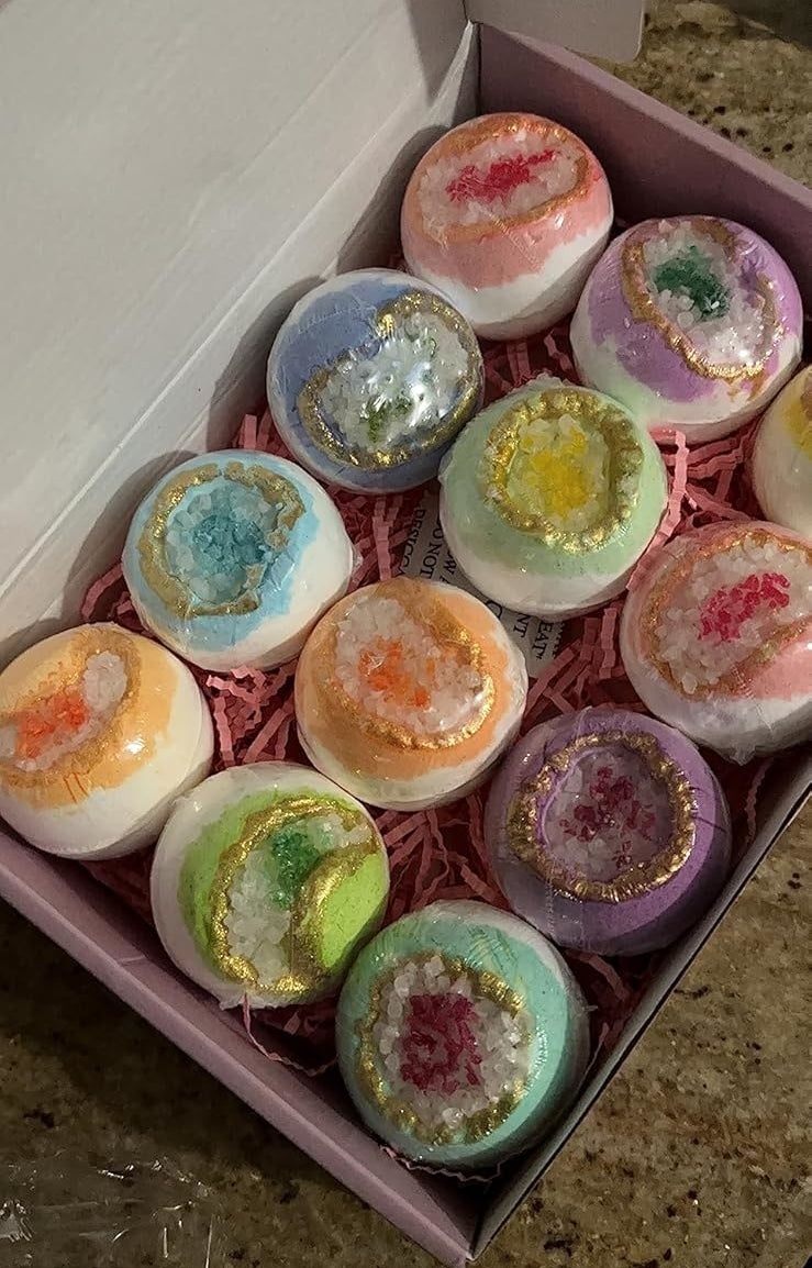 A neatly arranged box of twelve multicolored bath bombs with decorative patterns