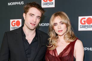 Robert Pattinson and Suki Waterhouse pose together in elegant evening wear at the GO Campaign event backdrop