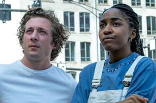 Jeremy Allen White and Ayo Edebiri in a scene from The Bear. Jeremy wears a white shirt, and Ayo wears a blue shirt with white overalls