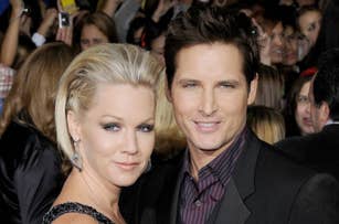Jennie Garth and Peter Facinelli pose together on the red carpet, both wearing elegant attire, with a crowd in the background