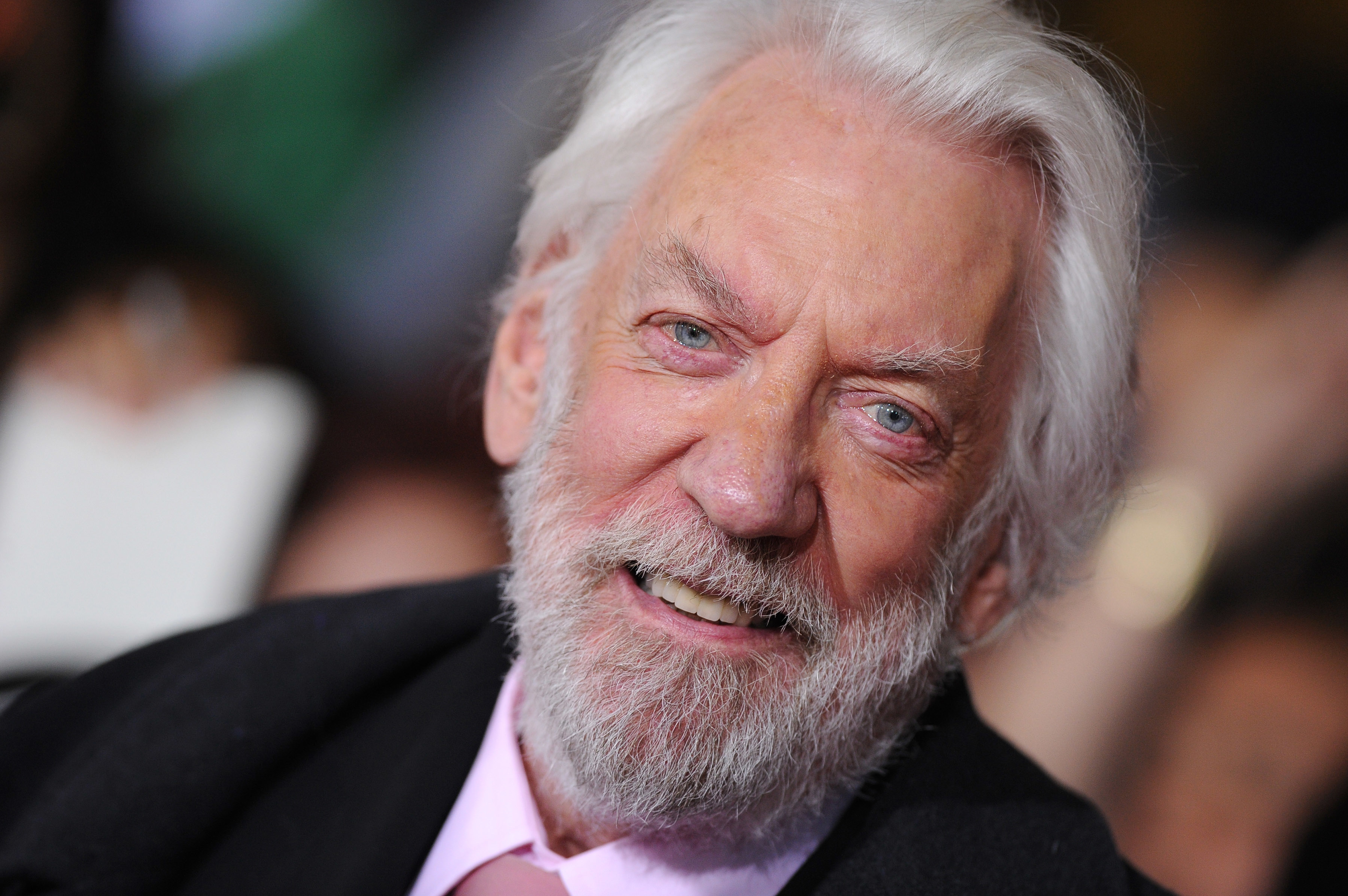 Donald Sutherland smiling while wearing a suit with a light-colored shirt, seen at a public event