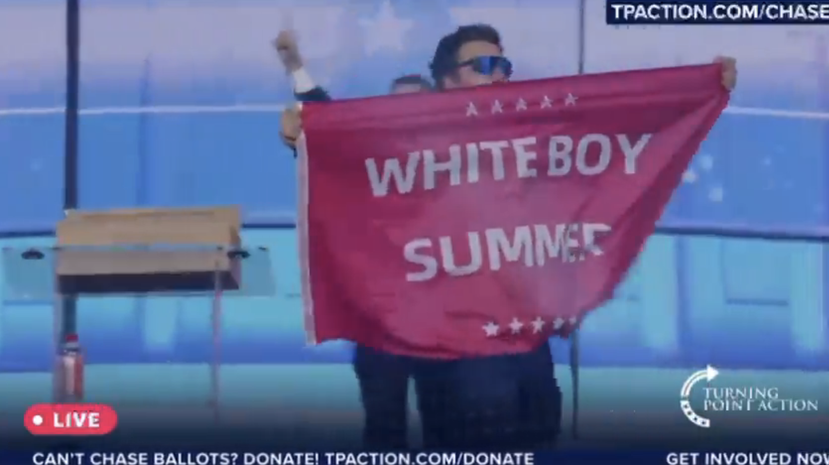 Jack Posobiec holds a banner reading &quot;Whiteboy Summer&quot; at a Turning Point Action event