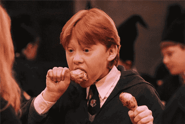 Rupert Grint en el papel de Ron Weasley, personaje de Harry Potter, comiendo dos muslos de pollo en el Gran Comedor de Hogwarts